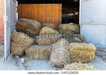 Square bale hay in front of stables