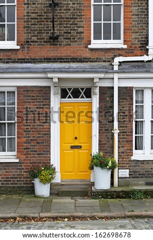 Old English house with brick wall and yellow door