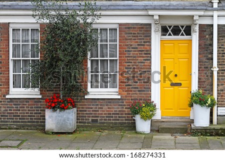 Old English house with brick wall and yellow door