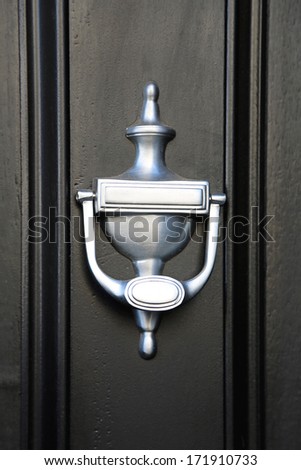 Modern silver knocker at black door