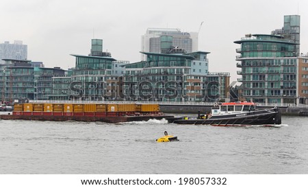 LONDON, UNITED KINGDOM - JANUARY 25: Barges and tugboat on the River Thames in London on JANUARY 25, 2013. Transporting waste by water in containers on barges pulled by tug in London, United Kingdom.