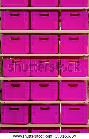 Shelf with pink plastic crates in warehouse