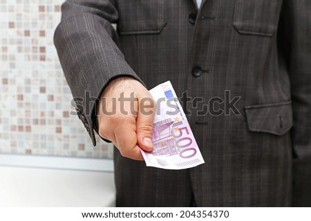 Man in suit giving biggest Euro banknote