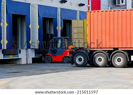 Forklift and trucks at cargo dock of warehouse
