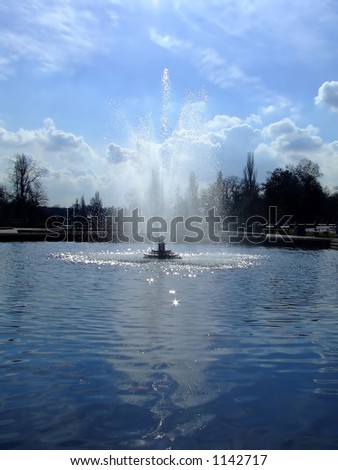 Fountain in the lake in the park on a sunny day, surrounded by nature