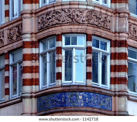 View to a window on the corner of a building with mosaic beneath