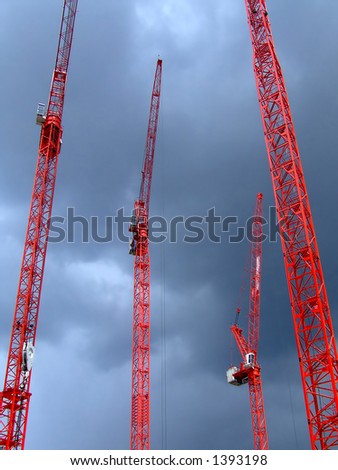 Four tall red cranes with sky in background