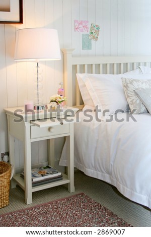 White night table with lamp and magazines