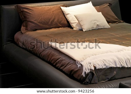 Modern double bed with brown sheets and pillows