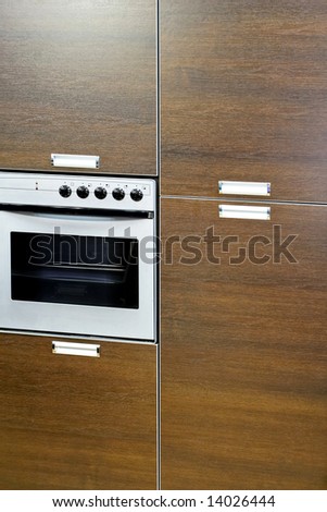 Electric oven in brown wood kitchen cabinet