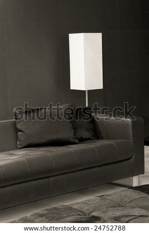 Dark interior with black sofa and white lamp