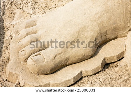 Big foot sculpture in sand at beach