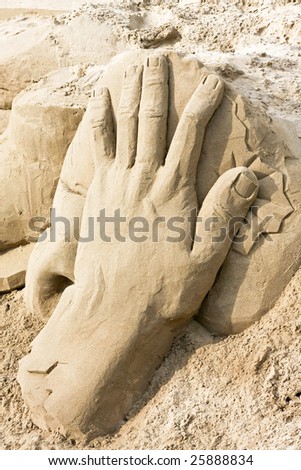 Big hand sculpture in sand at beach