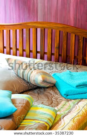 Wooden bed with sheets and pillows in purple room