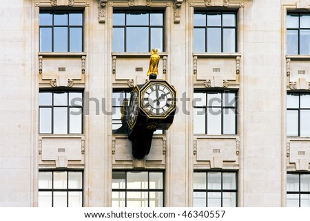 Public clock with owl statue at wall