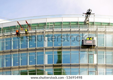 Workers simultaneously washing windows on office building