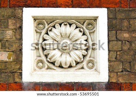 White stone ornament in brick wall facade