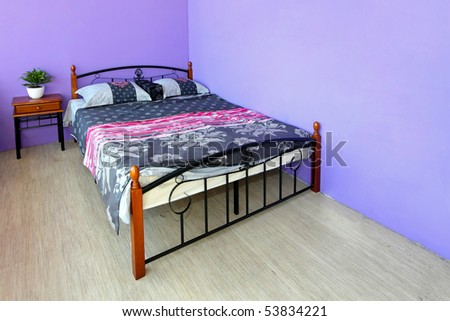 Girly bedroom with floral sheets and purple wall