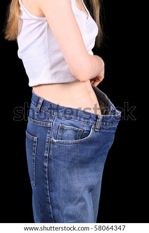Young girls measuring her weight loss trying old jeans