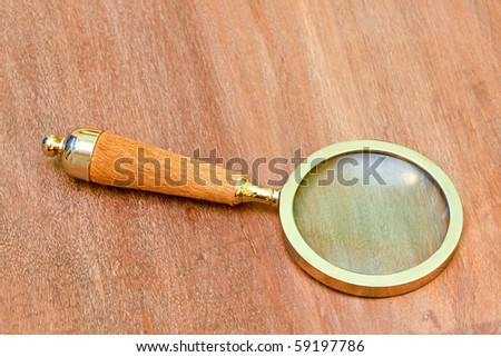 Close up shot of magnifying glass at wooden table