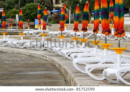 White plastic deck chairs with parasols in row