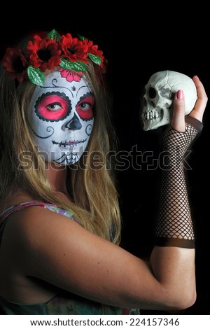 Beautiful girl with traditional Mexican mask, day of the dead, with the skull in his hand