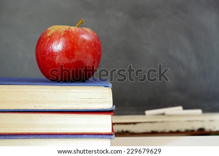 Back to school: apple on a pile of book in front of blackboard