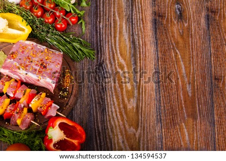 Raw fresh meat on cutting board with condiments and fresh vegetables
