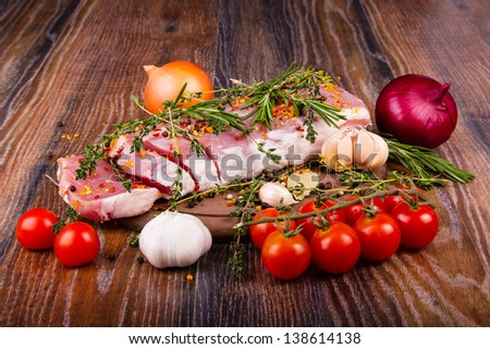 Raw fresh meat on cutting board with condiments and fresh vegetables