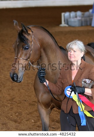 Woman and arabian horse with championship ribbon