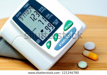 A sphygmomanometer on a  breakfast board indicates normotensive blood  pressure. Near by lying tablets.
