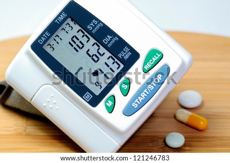 A sphygmomanometer on a  breakfast board indicates low blood  pressure. Near by lying tablets.