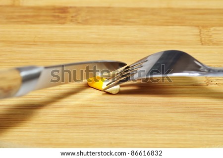 Capsule on wooden breakfast board with knife and fork