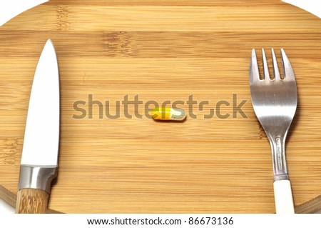 Capsule on wooden breakfast board with knife and fork