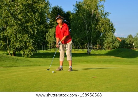Golf, woman golfer thrusting the ball into the hole