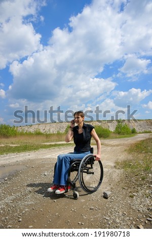 Disabled woman conversing on mobile phone outdoors, path in a quarry