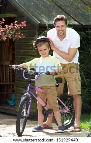 Father Putting Saftey Helmet On Son Before Bike Ride