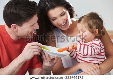Parents Feeding Baby Daughter From Bowl