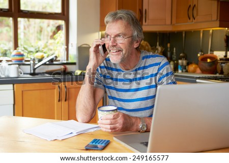 Mature Man Using Mobile Phone Looking At Home Finances