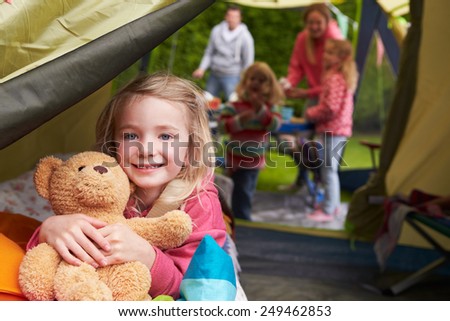 Girl With Teddy Bear Enjoying Camping Holiday On Campsite