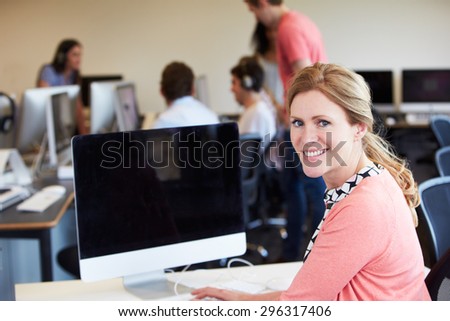 Female Tutor Using Computer In IT Class