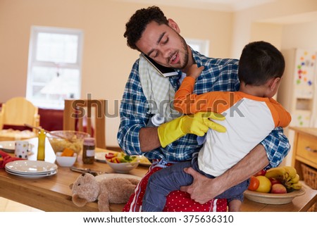Busy Father Looking After Son Whilst Doing Household Chores