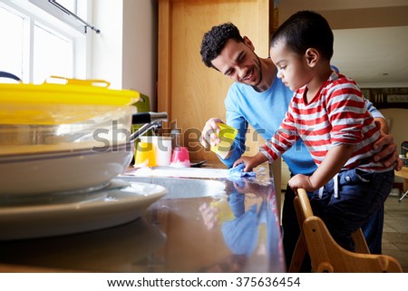 Son Helping Father To Wash Dishes In Kitchen Sink
