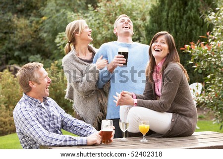Group Of Friends Outdoors Enjoying Drink In Pub Garden