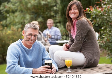 Couple Outdoors Enjoying Drink In Pub Garden