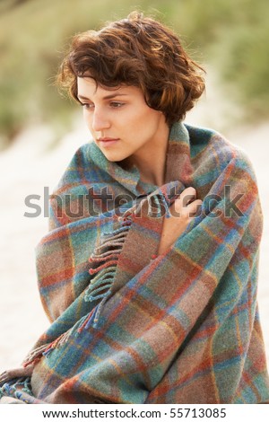 Young Woman Standing In Sand Dunes Wrapped In Blanket