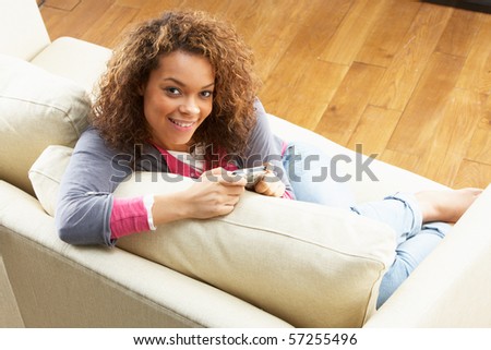 Woman Looking At Pictures On Digital Camera Relaxing Sitting On Sofa At Home