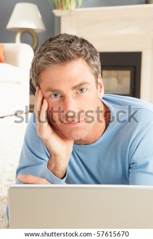 Man Using Laptop Relaxing Laying On Rug At Home