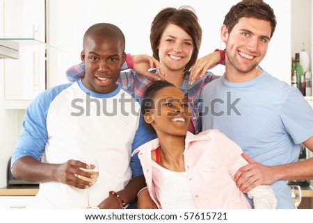 Group Of Young Friends Enjoying Glass Of Wine In Modern Kitchen