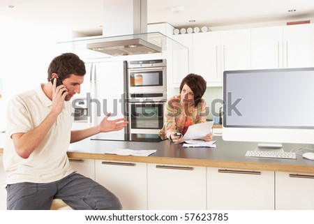 Young Couple Discussing Personal Finances In Modern Kitchen